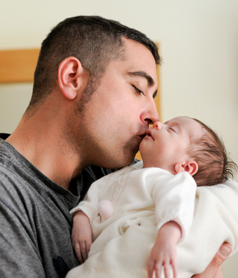 Father cradling a sleeping newborn with pride